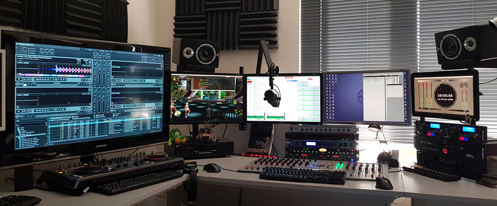 Wide picture of my studio setup, corner desk, with D&R airlab broadcast mixer built in on the right side, the Pioneer DDJ-T1 on the left side, 5 monitors and small studio monitor speakers.